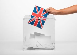 person-putting-united-kingdom-flag-card-into-ballot-box